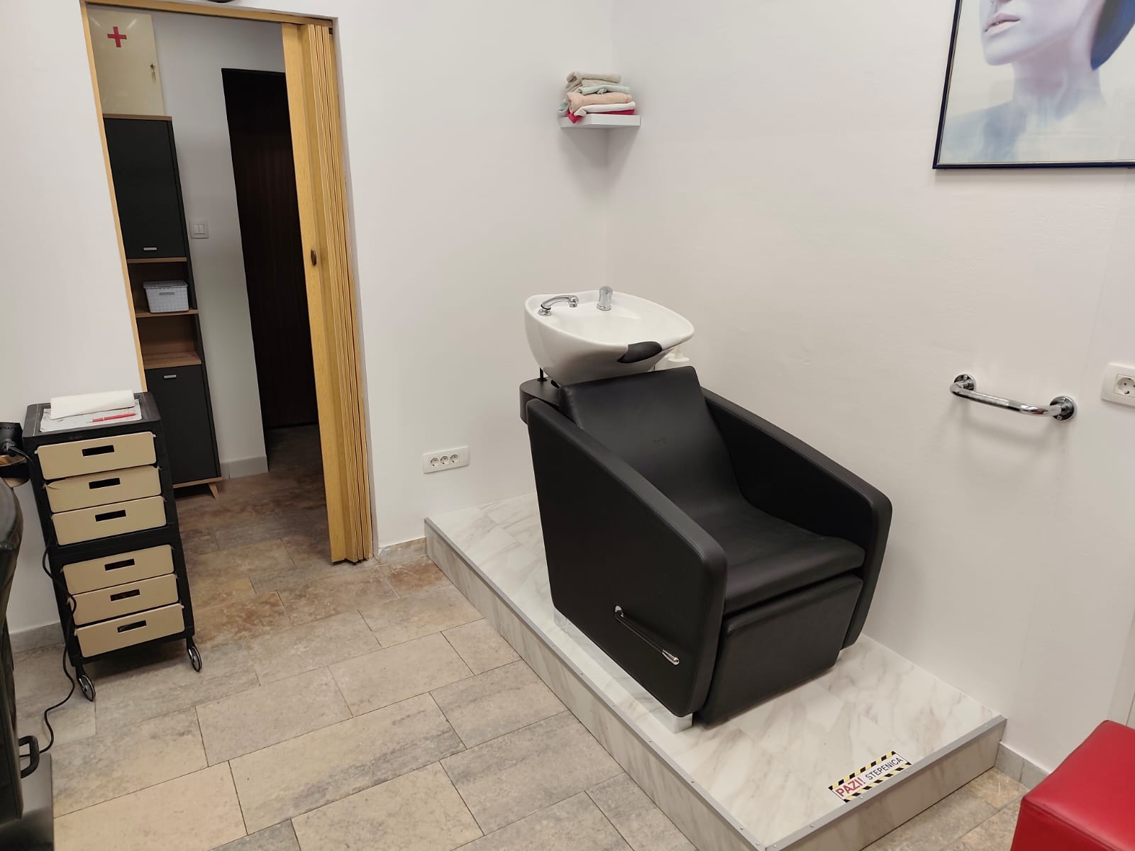 Crni stolac za pranje kose s bijelim umivaonikom u salonu Martina.